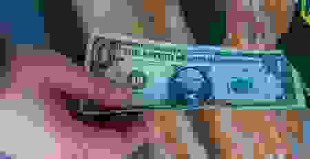 Customer inserting a one-dollar bill into a change machine, highlighting the importance of reliable bill acceptance in high-traffic business environments.