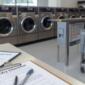 Modern coin laundromat interior with rows of washers and dryers and a setup checklist on a table in the foreground.