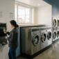 A coin-operated laundromat setting. Inside, a female customer is using a change machine